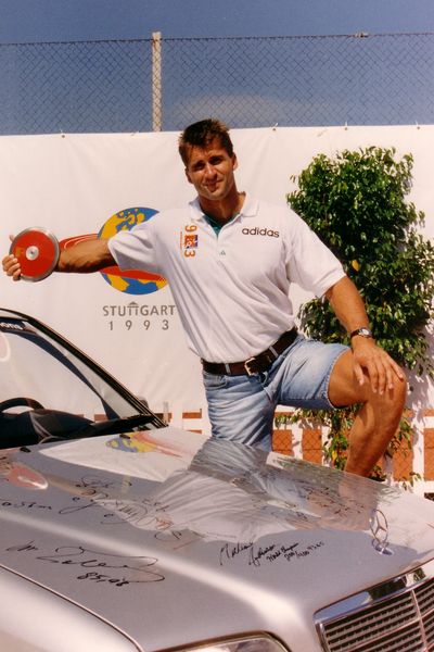 Lars Riedel (GER; 67,72 Meter; Diskuswurf) zeigt am Auto seine Spannweite mit dem Diskus.